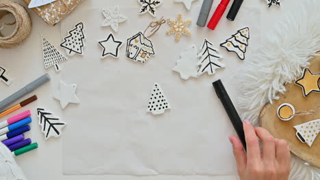 woman hand paints ornaments and decorates wrapped christmas gift