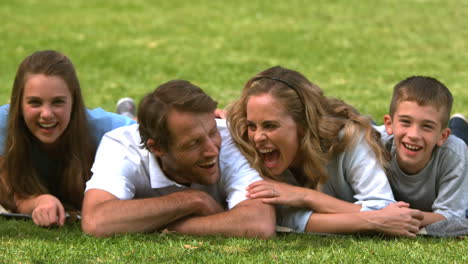 family lying on the grass and looking at camera