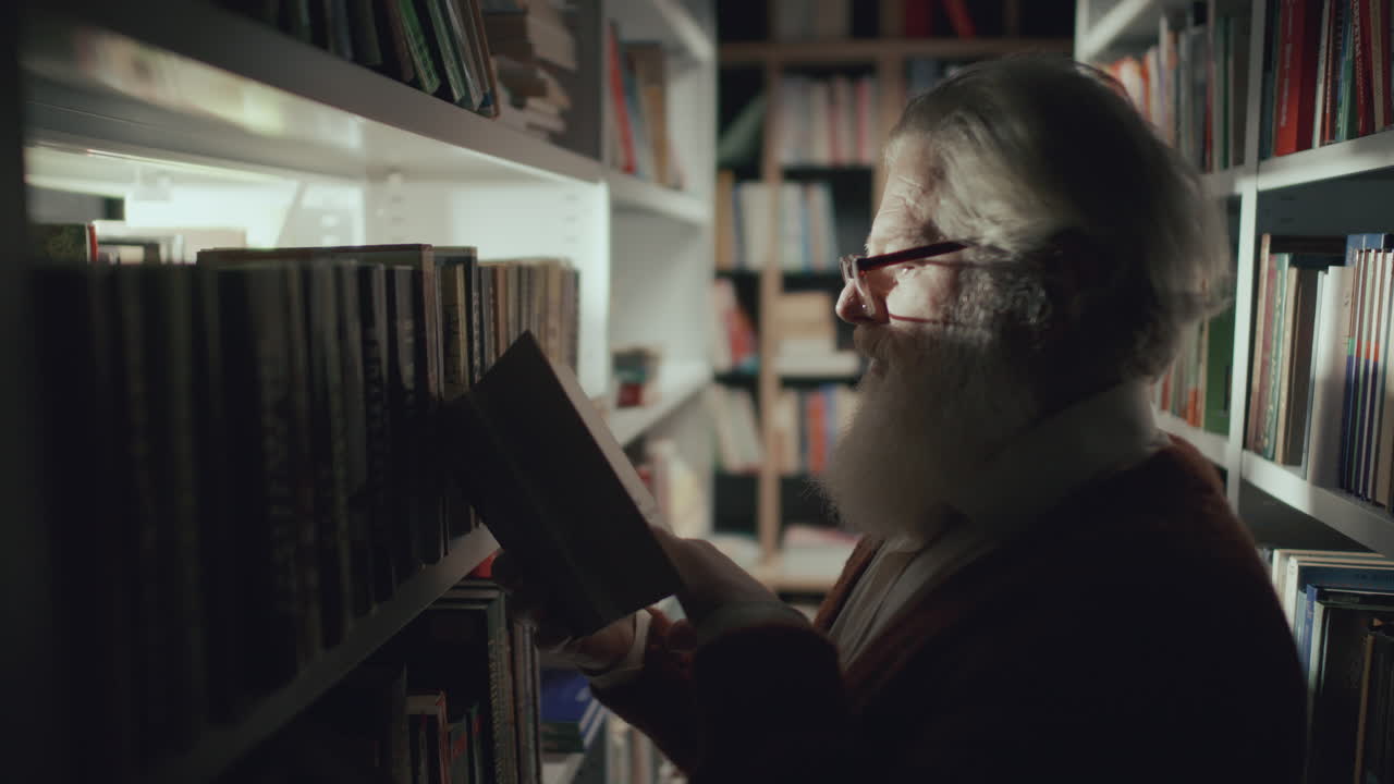 hombre anciano con gafas leyendo un libro durante una visita a la biblioteca