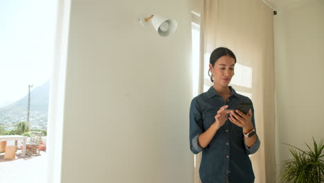 using smartphone, woman relaxing in morning at home, smiling contentedly