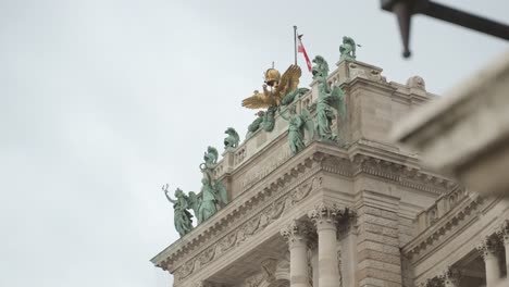 close up on the stunning hofburg imperial palace in vienna austria with its sculptures and eagle on the top while the austrian flag is waving in the wind and birds flying around on a cloudy day