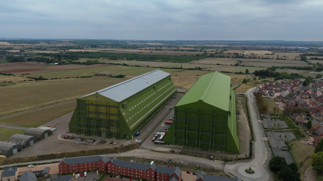 Aerial drone video capturing huge hangars, film studios, and movie sets near Bedford England UK surrounded by countryside and summer homes