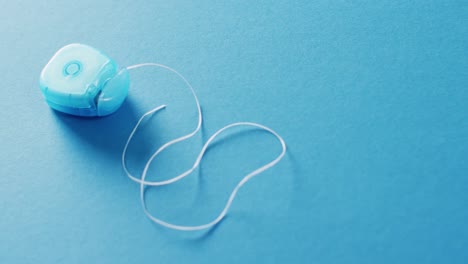 video de un primer plano de hilo dental sobre un fondo azul