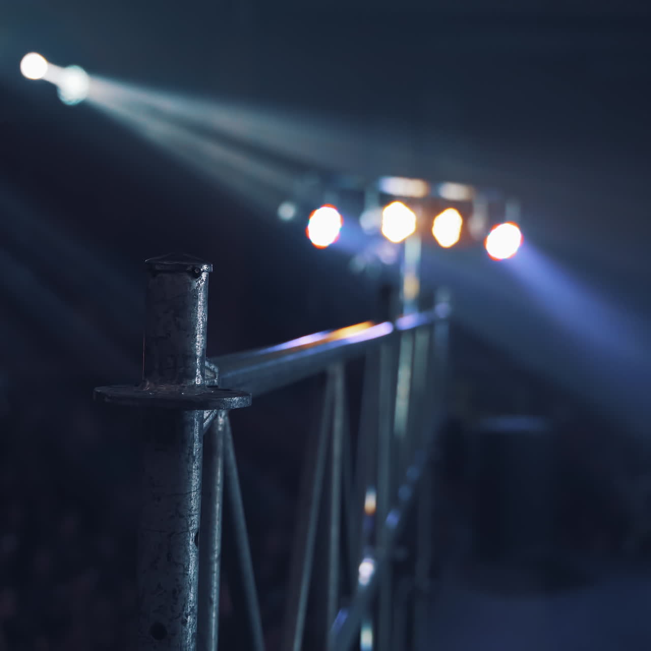Projectors view to the stage on the background of blur audience. Flashing lights shining from spotlights in the studio inside.