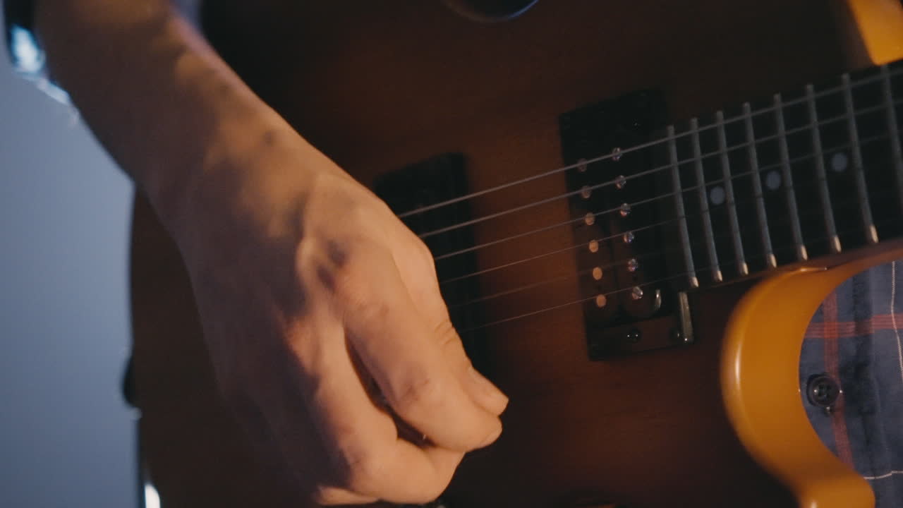 Primo piano di una mano che strimpella una chitarra elettrica.