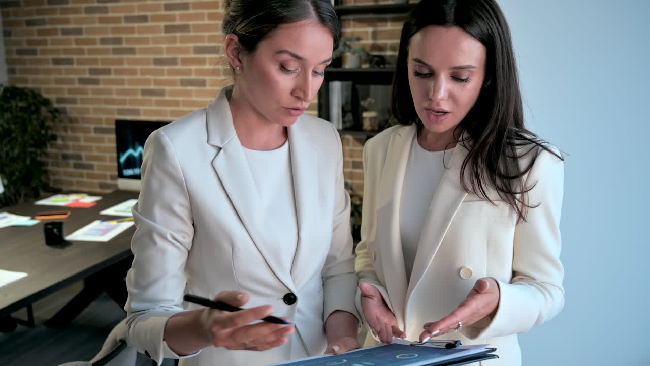 Duas mulheres conversando e apontando para um tablet em um escritório