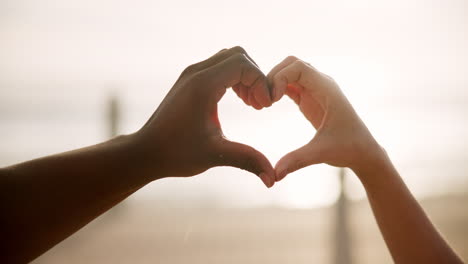 interracial couple making a heart shape with their hands