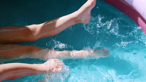 children spraying water with their feet in an inflatable pool