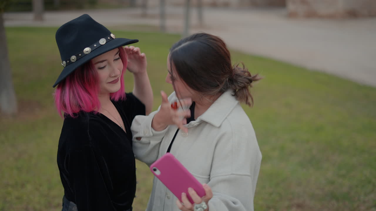 두 친구가 공원에서 셀피를 찍고 있다.