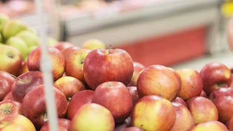 una mujer con guantes de goma recoge manzanas frescas y las pone en una bolsa de plástico en un supermercado, de cerca. protección contra el coronavirus.