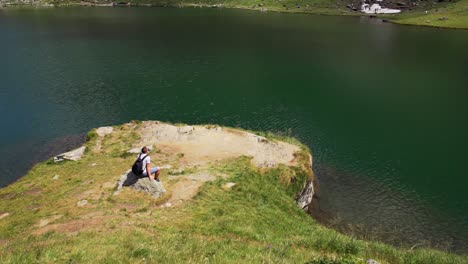 Man-Resting-Near-Balea-Lake-In-Romania---aerial-shot