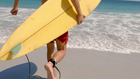 handsome man running in the water with surfboard