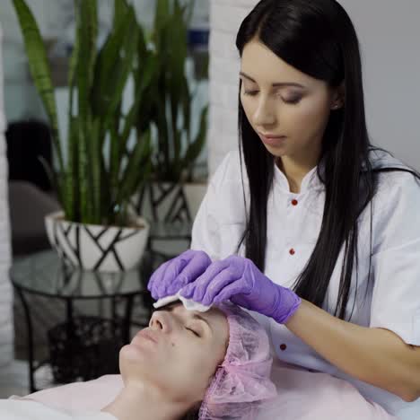 a beautician cleans the skin of the client's face before the procedure using a sponge in the cosmetology studio. close-up