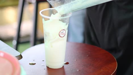 coconut smoothie overflows from a tall glass