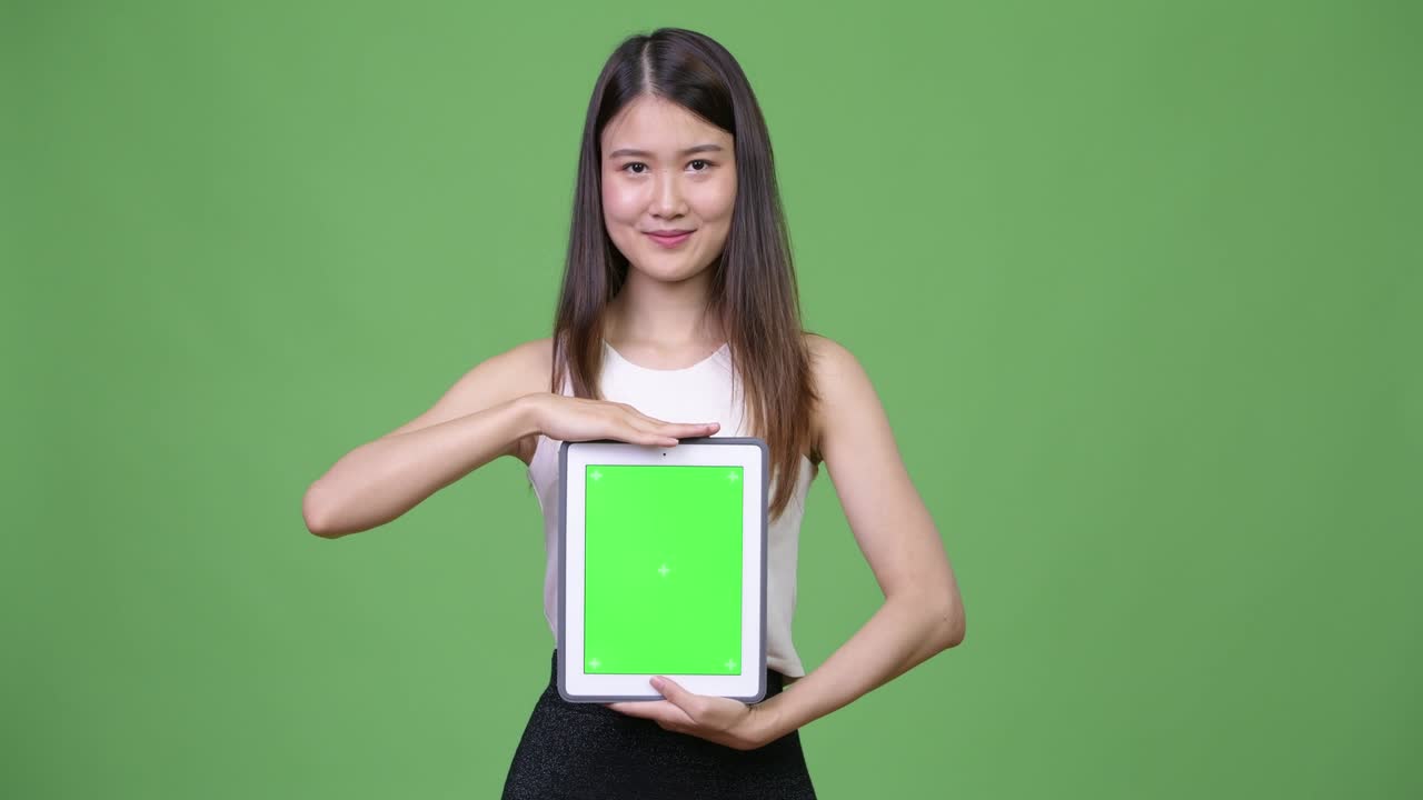 젊은 아름다운 아시아 사업가 여성이 디지털 태블릿을 보여줍니다.