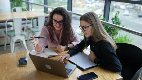 business discussion between two colleagues sitting at the table in front of laptop. comfortable working place in a large office.