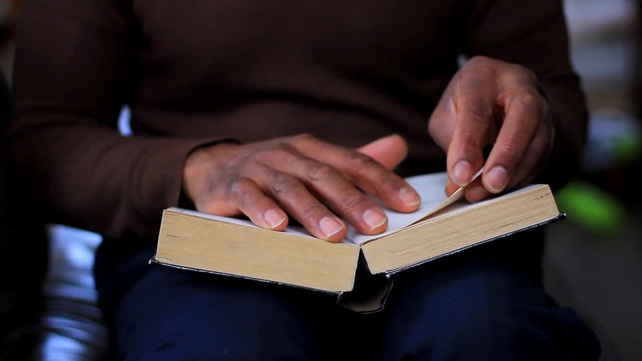 Uomo di colore che tiene la Sacra Bibbia dopo aver pregato in chiesa, filmato d'archivio.