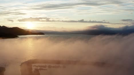 rolling clouds over calm lake in the archipelago of norway during sunrise