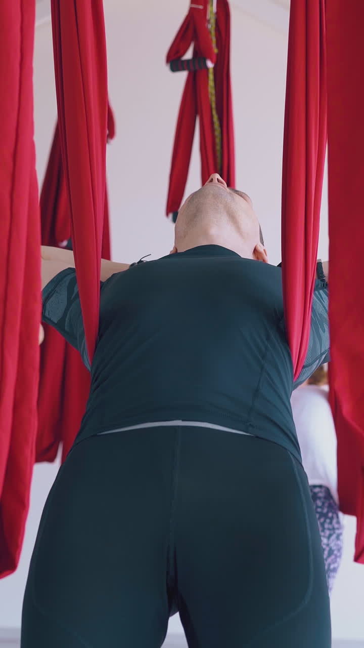 sportsmen practice meditation putting hands behind head and relax in aerial fly yoga hammocks close view