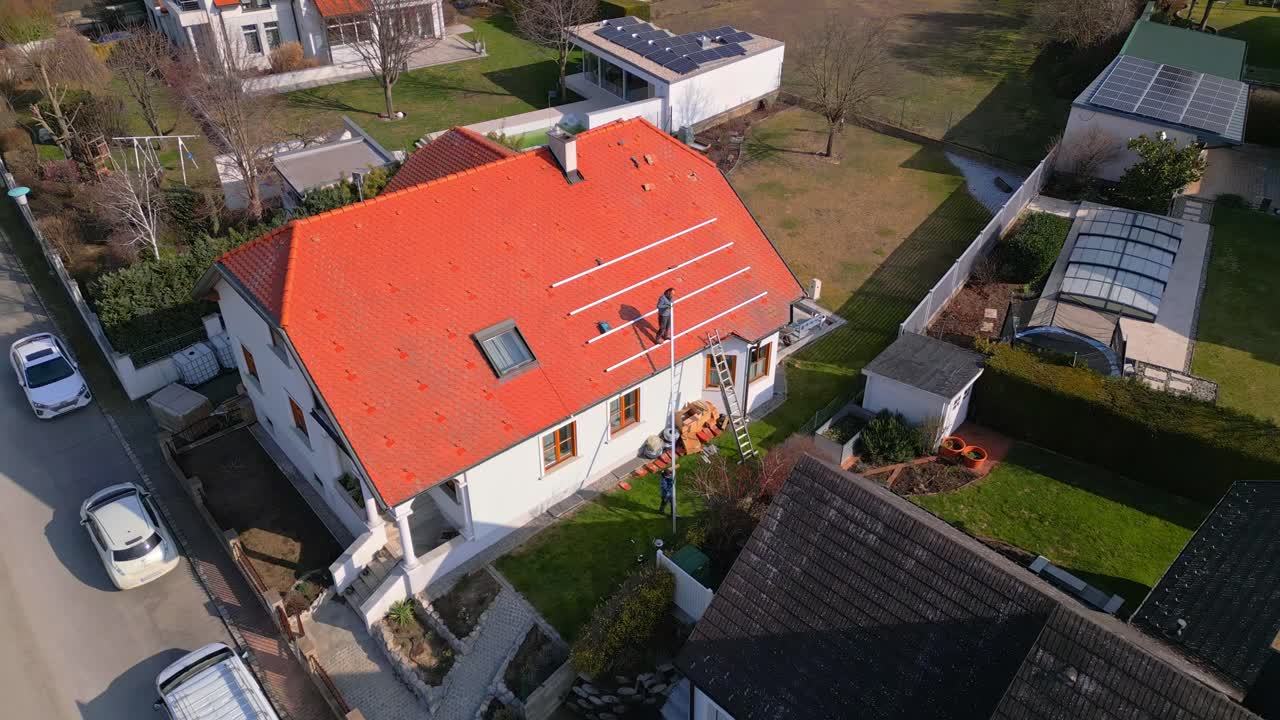 Workers Putting The Solar Panels Mounting Brackets On Roof Of A House - aerial drone shot