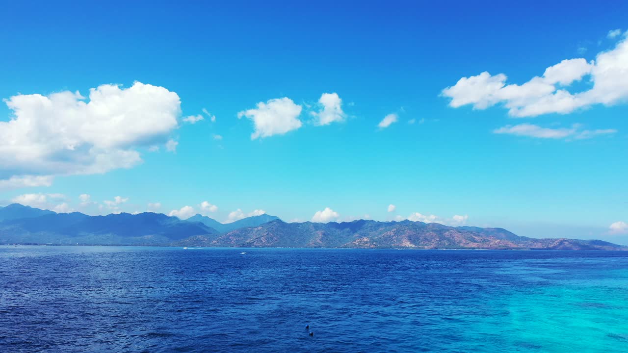 Vivid colors of peaceful seascape with blue azure sea around mountains of tropical islands under bright sky with white clouds, Bali