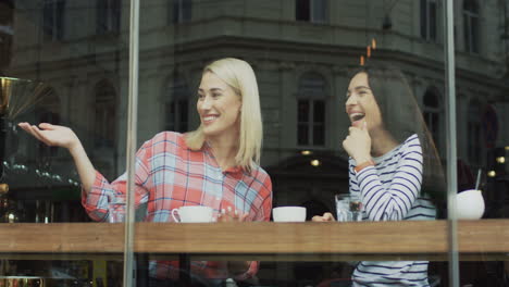 two beautiful women chatting cheerfully while drinking coffee in a cafe