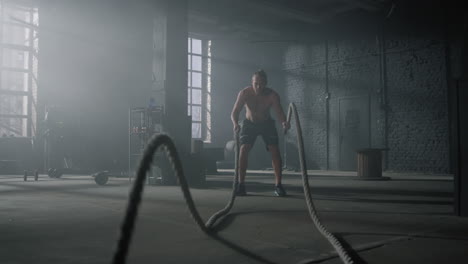 hombre practicando ejercicio con cuerdas de batalla. deportista haciendo entrenamiento funcional