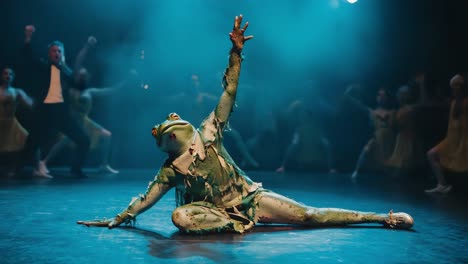 a person in a frog costume performing on stage with dancers in the background