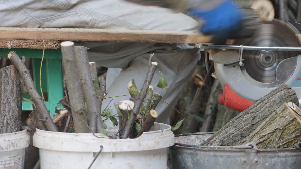 Men's hands in gloves sawing firewood and puts them in buckets.