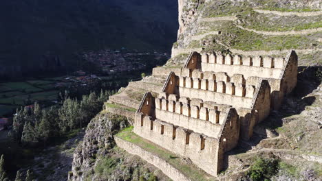 Aerial-pan-right-of-historic-town-site-of-Ollantaytambo-cut-out-of-hillside-in-Peru