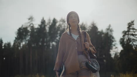 female explorer looking around in forest on sunny day