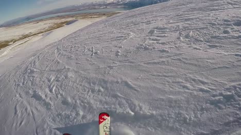 Perspective-of-a-skier-slaloming-down-a-slope-with-mountains-and-lake-in-the-distance