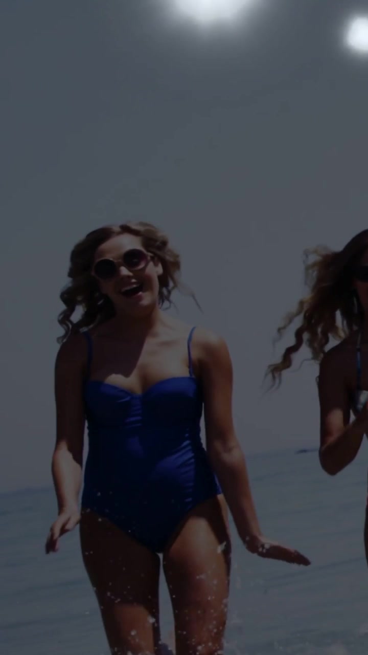 Video verticale: Donna in tailleur blu che entra, poi corre e schizza tra le onde, usando bagliori dell'obiettivo.