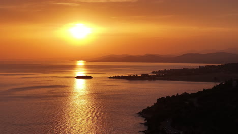 sunset over the ocean with a small island in the foreground