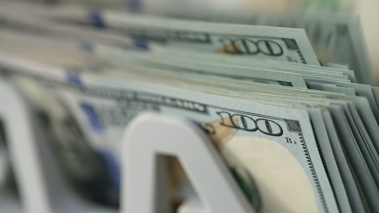 New hundred dollar bills quickly falling on the holder of machine. Close up. Financial equipment at work. Blurred backdrop.