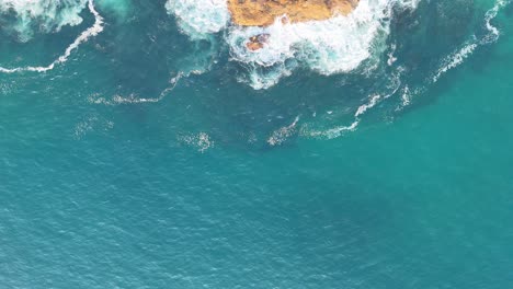 Atemberaubender-Blick-Von-Oben-Auf-Eine-Schroffe-Klippe,-Die-Auf-Das-Turbulente-Azurblaue-Wasser-Trifft:-Der-Kontrast-Der-Natur-Im-Spiel