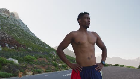 african american man standing and flexing his muscles on a coastal road