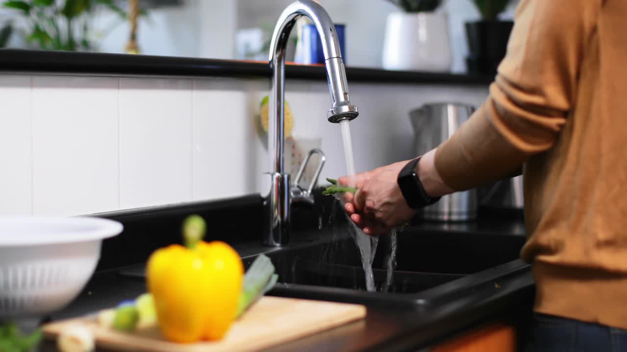 Hombre lavando verduras con agua frente al grifo 4k