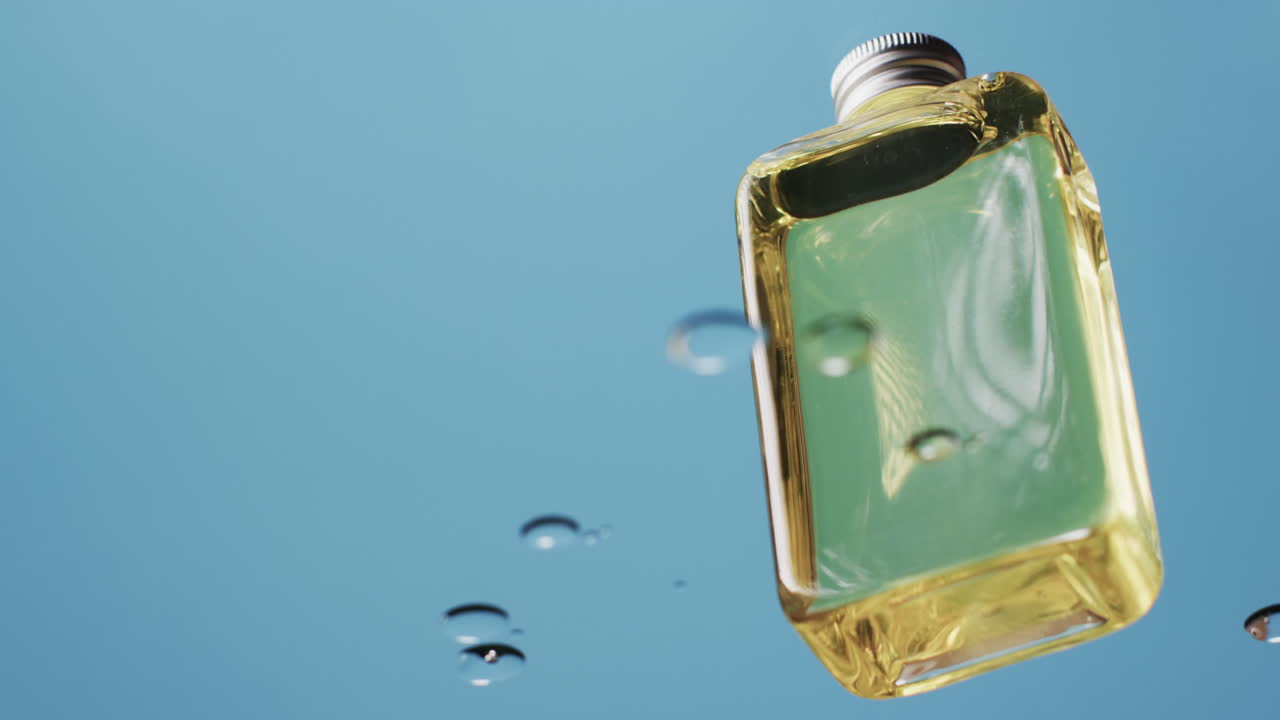 video de una botella de producto de belleza en agua con espacio de copia en fondo azul