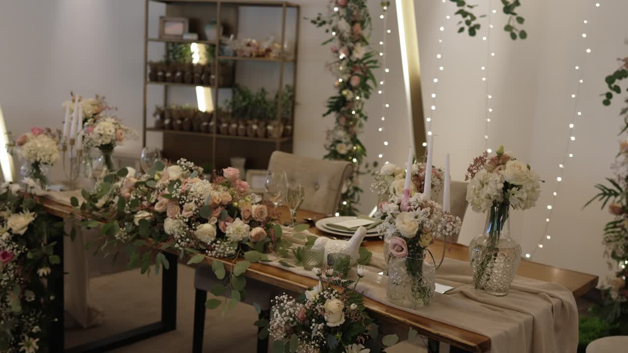 Mesa principal de boda romántica con arreglos florales suaves y acentos de velas brillantes