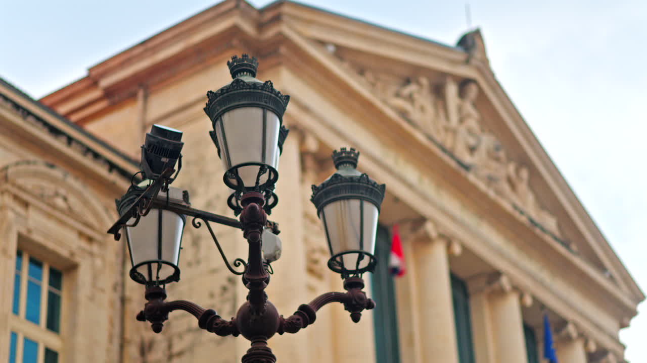 Close up of a street lamp with a blurred view of the Nice courthouse on the background
