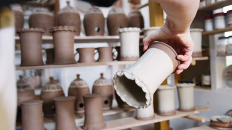 close up of male potter applying glaze to clay vase in ceramics studio