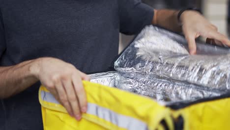 mensajero con mochila mira adentro para obtener detalles sobre el recibo del pedido, vista recortada