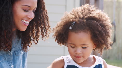 mixed race mother and daughter blowing bubbles, close up