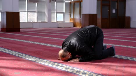 masked old man kneels in prayer during ramadan