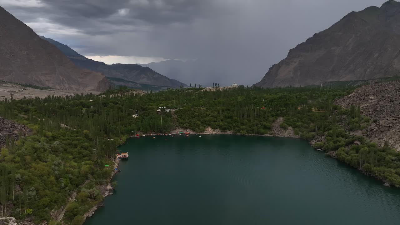 imágenes aéreas descendentes de un dron sobre el lago en pakistán mirando hacia la montaña y los árboles altos y verdes