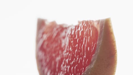 micro video of close up of slice of red grapefruit with copy space on white background