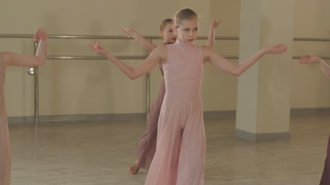 un grupo de jóvenes estudiantes de ballet con ropa de baile negra practicando posiciones en un amplio estudio de ballet con pisos de madera y barras montadas en la pared. expresiones enfocadas y movimientos sincronizados.