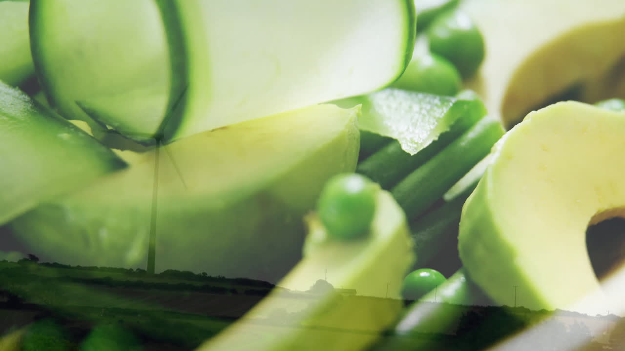 Wind turbines spinning over landscape with fresh green vegetables in foreground