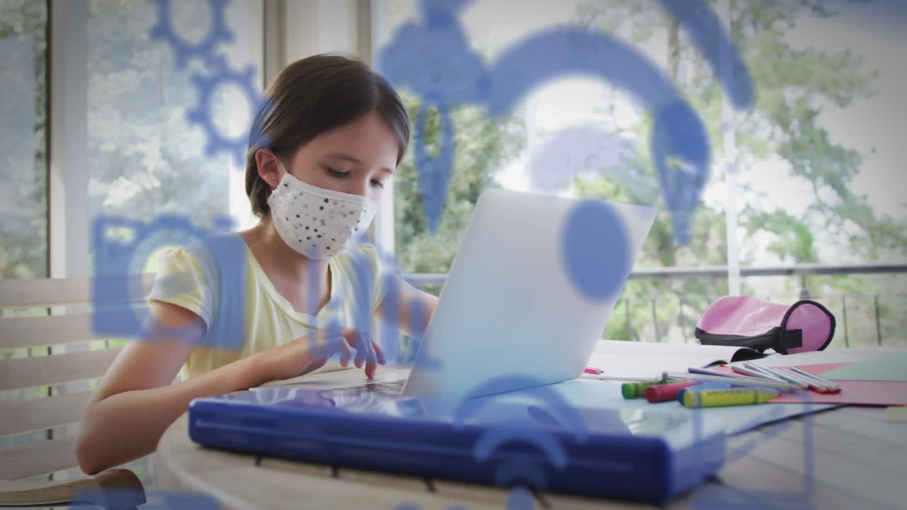 집에서 노트북을 사용하여 얼굴 마스크를 입은 백인 소녀 위에 디지털 아이콘의 애니메이션